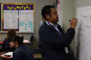 male writing on large sticky note hanging on the wall