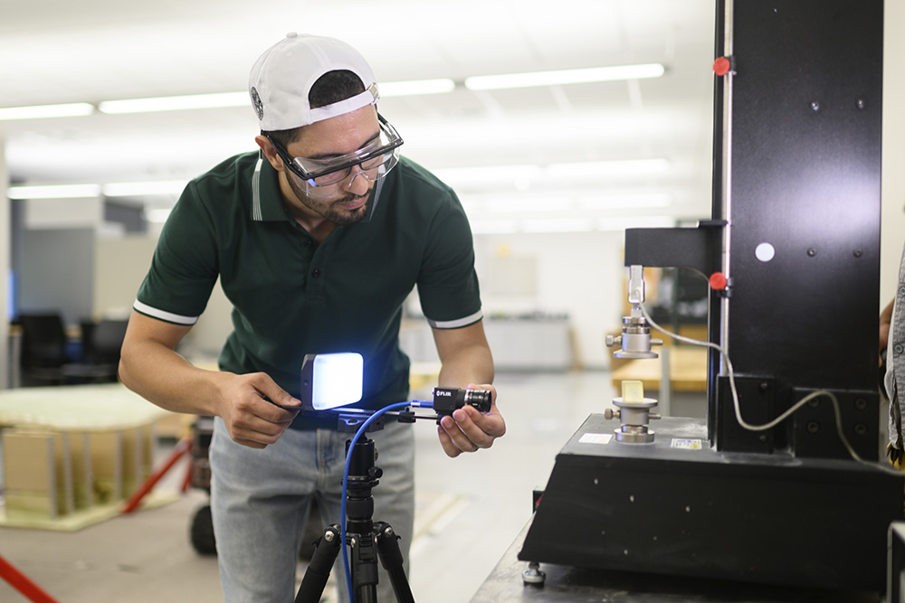 Mechanical engineering student adjusts a camera and light for an experiment