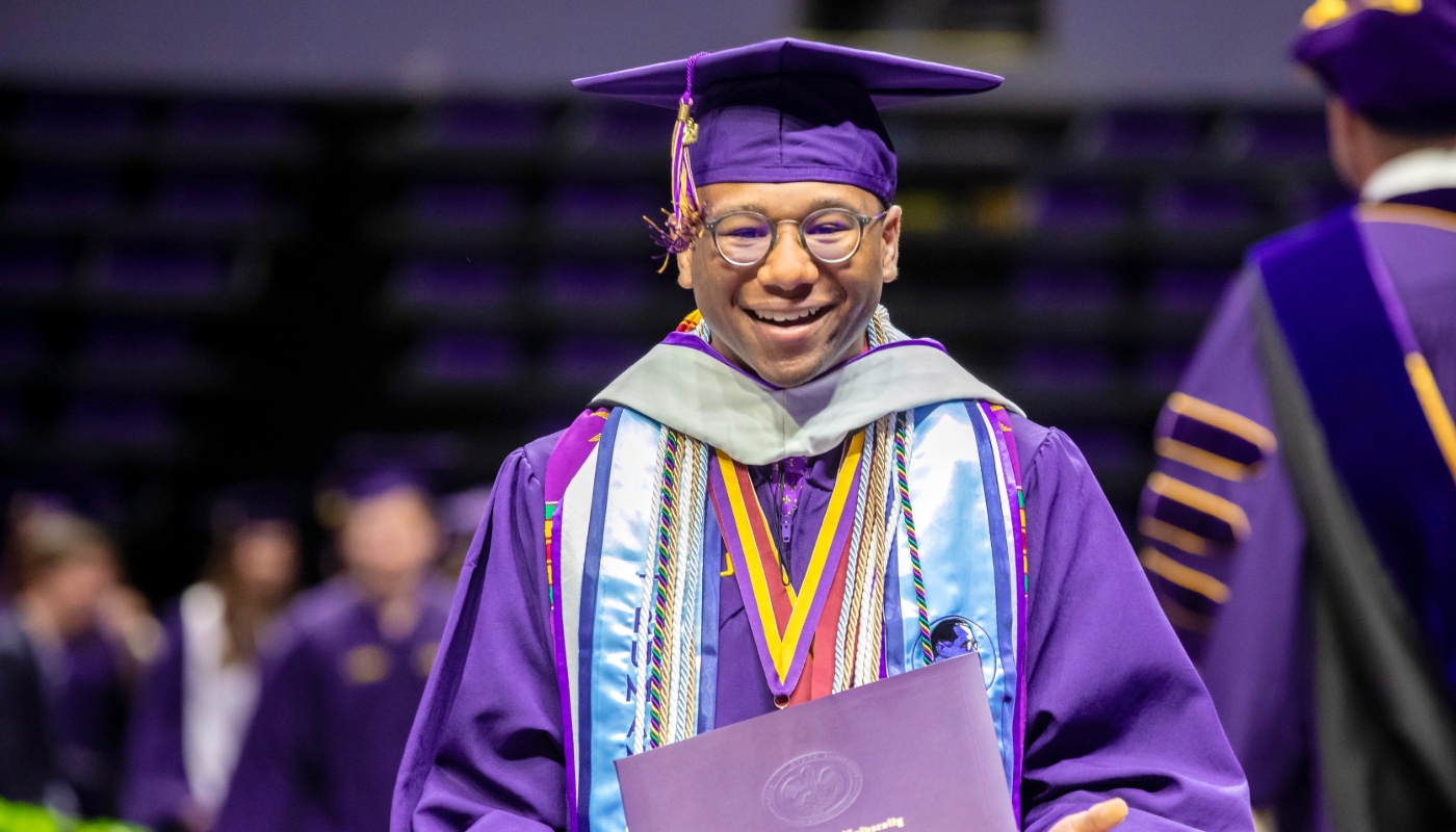 Photo of LSU Honors College student Tay Moore walking across the stage at graduation