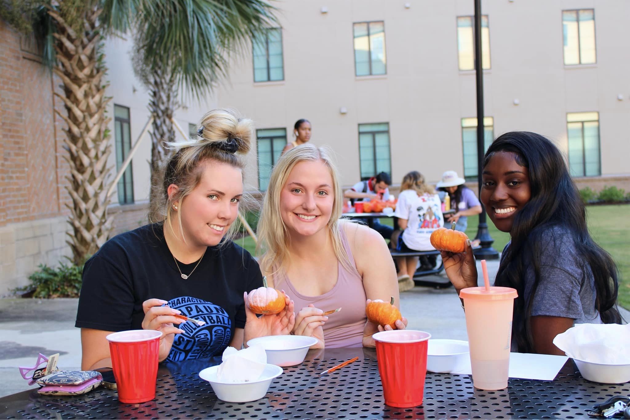 Students posing for a photo with painted pumpkins outside of Marsh Hall.